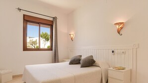 Una camera da letto con un letto, un comodino, una lampada a parete e una finestra vista.