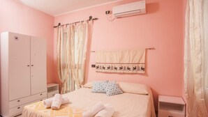 A bedroom with a bed, a wardrobe, a nightstand, an air conditioning unit, and a towel rack.