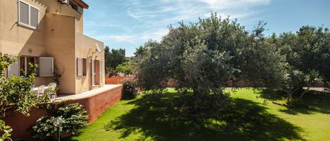 Una casa con jardín, un patio con sillas y una antena parabólica.