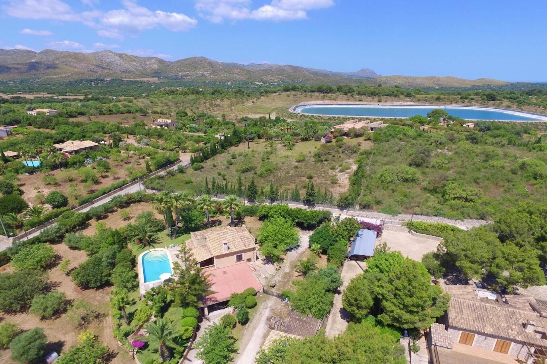 Vue aérienne d’un quartier résidentiel avec des maisons, une piscine et une grande étendue d’eau.