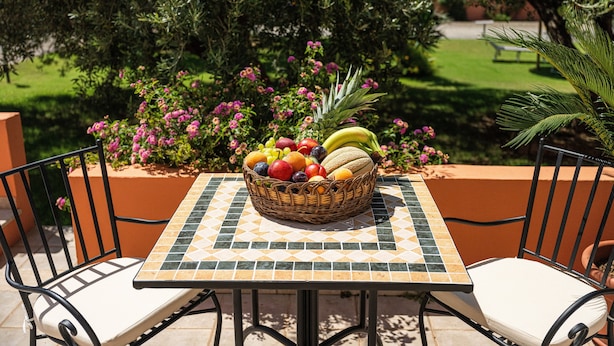An outdoor table with a fruit basket, two chairs, and a tiled table surface. - Studio Apartment 'Villa Erica Appartamento Lesley' with Mountain View, Wi-Fi and Air Conditioning (villa san pietro)