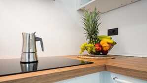 A kitchen counter with a stainless steel kettle, a fruit bowl with bananas, grapes, and a pineapple, and a white cabinet with a towel rack. - Studio Apartment 'Villa Erica Appartamento Lesley' with Mountain View, Wi-Fi and Air Conditioning (villa san pietro)