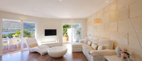 A modern living room with a sofa, a coffee table, and a TV mounted on the wall.