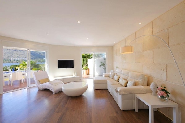 A modern living room with a sofa, a coffee table, and a TV mounted on the wall.