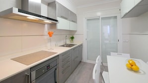 Una cocina moderna con horno empotrado, un lavamanos y una encimera blanca.