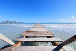 A wooden pier extending into a calm sea with clear skies.
