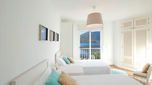 Un dormitorio con dos camas, un ventanal con vistas y un balcón.