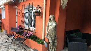 Un área de estar al aire libre con una mesa, sillas, una estatua y un sofá de mimbre.