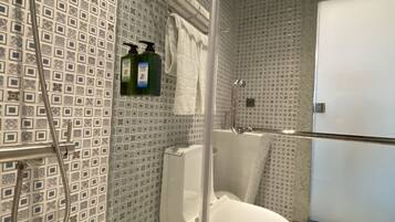 A modern bathroom with a glass-enclosed shower, a white toilet, and patterned tile walls.