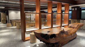 A modern interior with wooden display cabinets and a unique carved wooden table. - Weifeng Boutique Business Hotel (Pingtung)