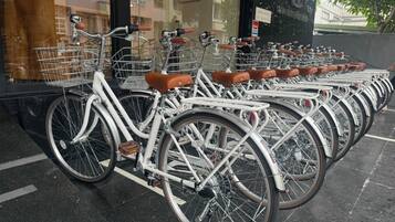 A row of white bicycles with brown leather seats parked outside a building.