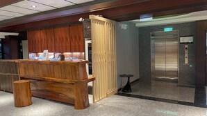 A reception area with a wooden counter, a wooden privacy screen, an elevator, and a small table. - Weifeng Boutique Business Hotel (Pingtung)