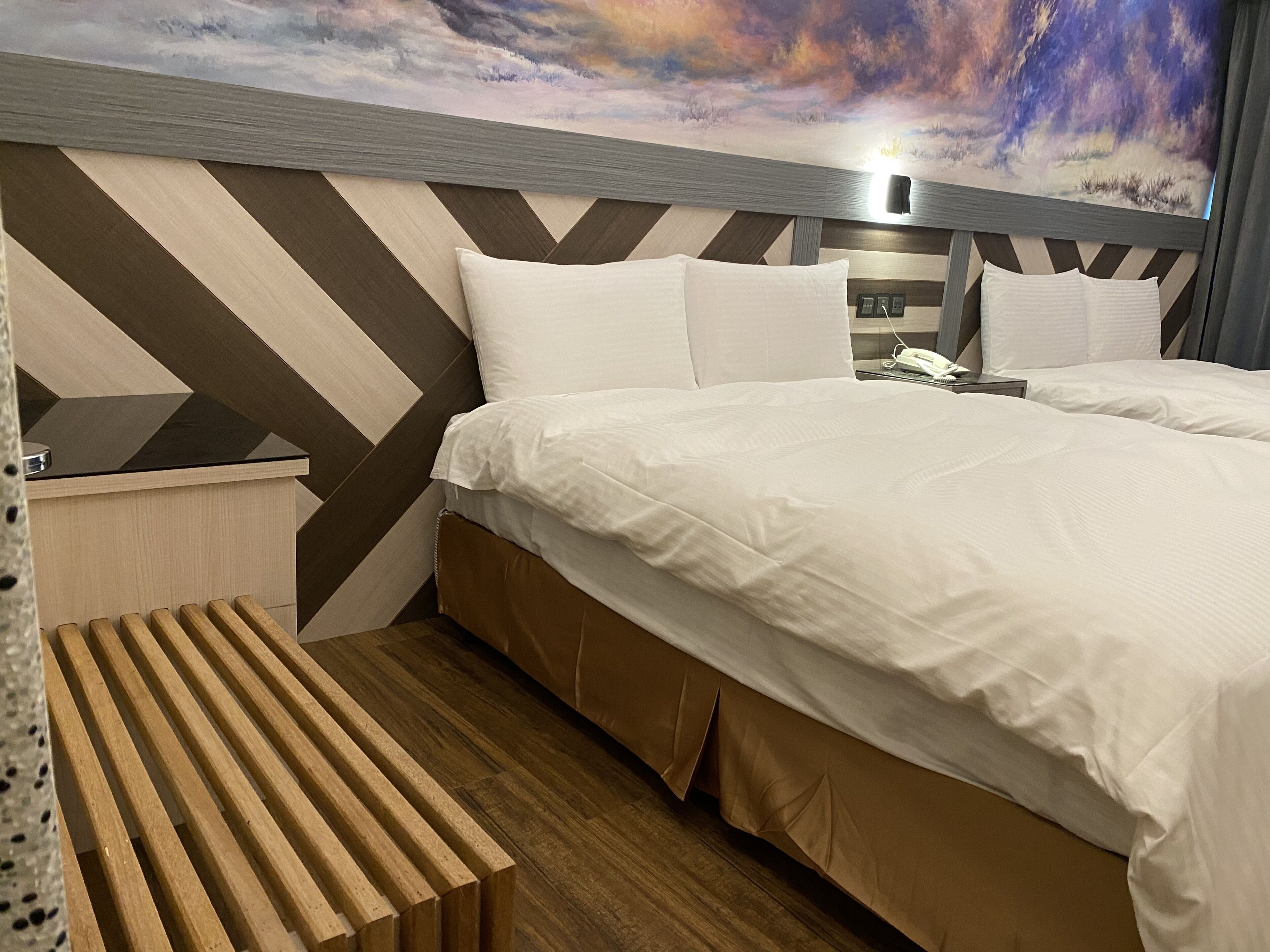 Une chambre d’hôtel avec un lit, une table de chevet et un téléphone fixé au mur.