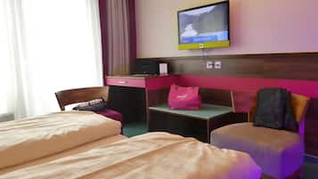 A hotel room with two beds, a desk, a television, and a pink bag on the desk.