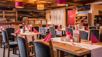 Ein Restaurant mit Holztischen und -stühlen, rosafarbenen Servietten und einem Menüständer.