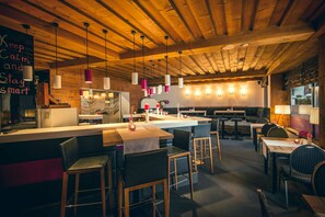 Un restaurante con techo de madera, barra y zona de estar.