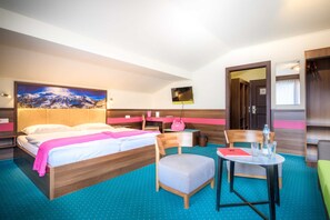 Habitación de hotel con cama, escritorio, silla, mesa y espejo.