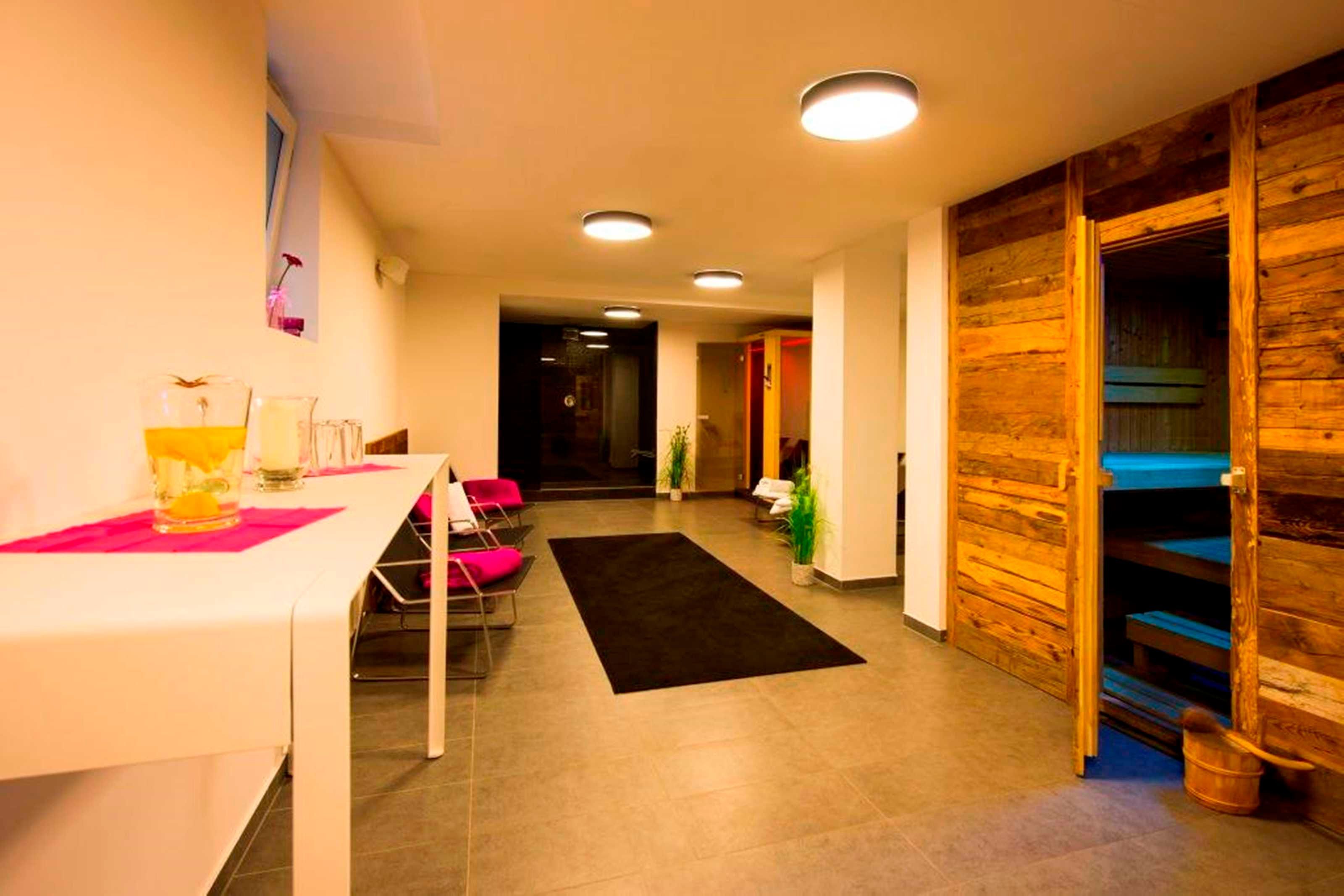 Un hall d’hôtel comprenant un comptoir d’accueil, des chaises, un tapis noir, des murs en bois et un escalier.