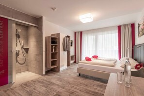 Une chambre d’hôtel moderne équipée d’une douche, d’un lit, d’une table de chevet et offrant une vue sur la ville.