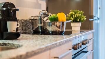 A kitchen with a coffee maker, a bowl with peppers, and a potted plant.