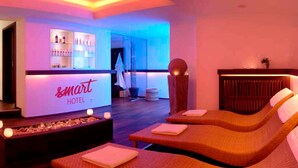 Hall d'hotel con reception, area bar e sala massaggi con due lettini.