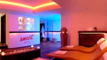 Eine Hotlellobby mit Empfangsbereich, Bar und einem Massagezimmer mit zwei Massagetischen.