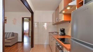 A modern kitchen with a stainless steel refrigerator, a coffee maker, and wooden cabinets.