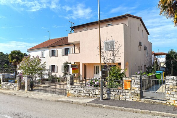 A two-story building with a stone facade, multiple windows, and a red-tiled roof.