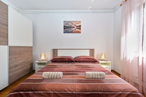 A neatly made bed with striped bedding, two bedside lamps, and a framed picture on the wall. - Apartment 2074/34552 (Istria - Poreč), 600m from the beach (Poreč)