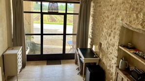A room with a large window, a desk, a chair, a small cabinet, and a stone wall. - La Verrière, Très Jolie Chambre Indépendante Avec Courette Abritée (Bonnieux)