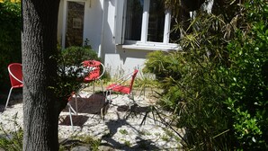 A white building with a window and a door, surrounded by greenery and a tree. - Cozy Home Near Sea and Arago Market, 2-Star Comfort (Les Sables-d'Olonne)