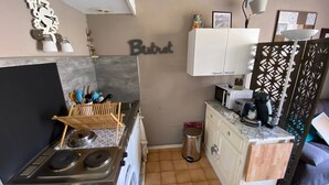 A compact kitchen with a stove, microwave, and sink, a washing machine, and a cabinet with a decorative sign above.