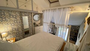 A bedroom with a bed, a bedside table, a mirror, and a wardrobe.