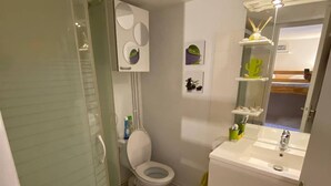 A bathroom with a glass shower enclosure, a toilet, and a sink with a mirror above it.