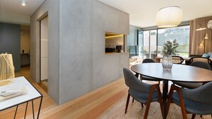 Een moderne eetruimte met een ronde tafel, grijze stoelen en een hanglamp.