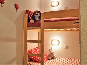 A bunk bed with a ladder, a stuffed dog, and a unicorn toy. There are heart-patterned pillows and a red blanket. - Cozy 2-Room Apartment for 6 with Balcony, Near Slopes, Pet-Friendly (Risoul)