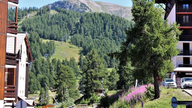 A mountain view with a ski resort, including buildings and a parking area. - Cozy 2-Room Apartment for 6 with Balcony, Near Slopes, Pet-Friendly (Risoul)