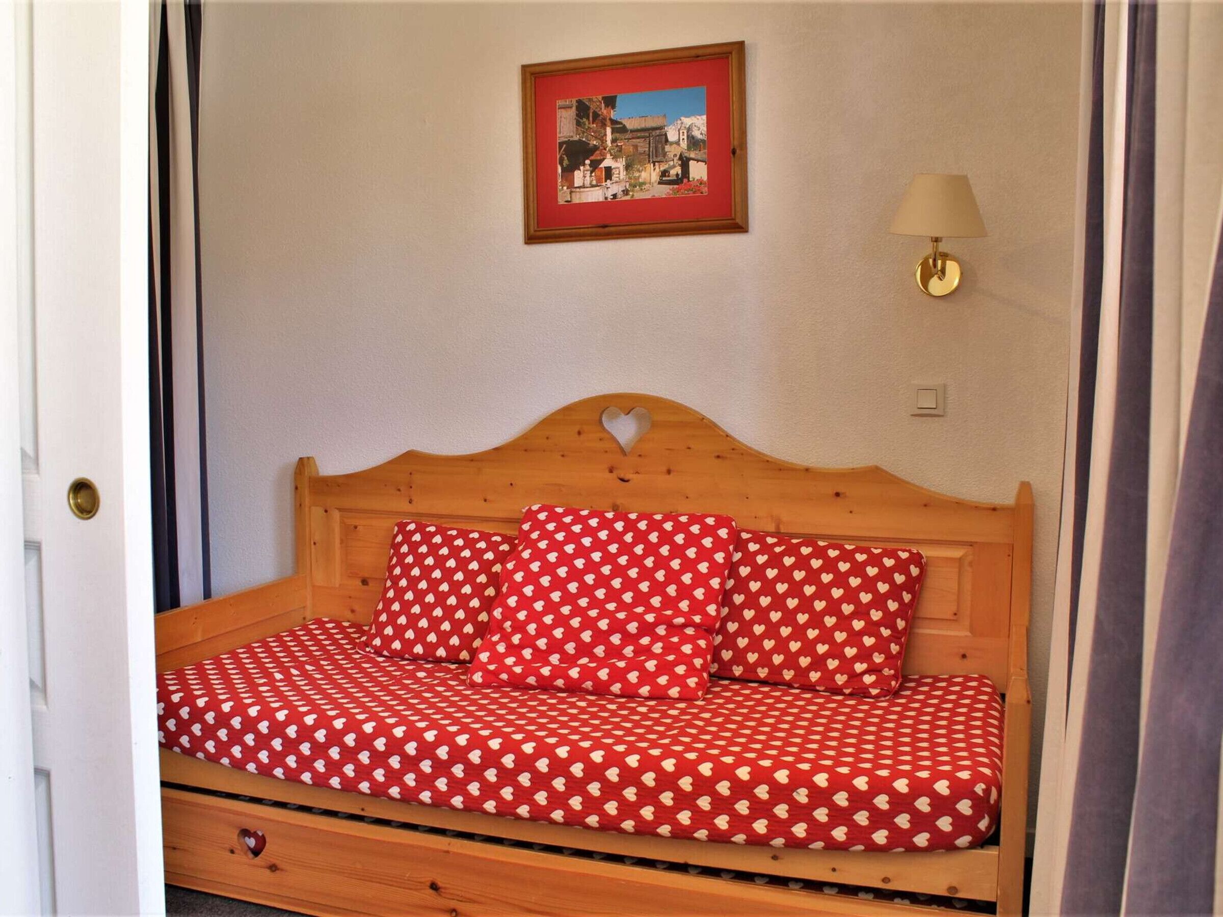 Una cama con cabecera de madera y ropa de cama estampada con corazones.