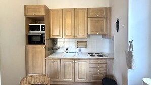 Una cocina compacta con armarios de madera, microondas, estufa y lavabo.