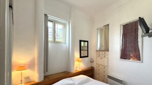 Un dormitorio con una cama, lámparas de noche, un tocador, un espejo y una ventana.