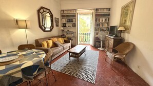 Una sala acogedora con un sofá, una mesa de comedor y una estantería.
