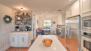 A modern kitchen with white cabinets, a stainless steel refrigerator, and a wooden bowl on the island. - Spacious Getaway ~ 12 Acres, Views, & Hot Tub! (Strawn)
