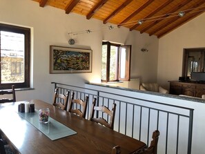 Enjoy meals in this cozy dining area with a table, chairs, and a glass-top surface, surrounded by a painting and a window with a view.