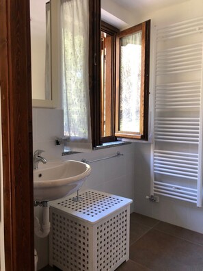Bathroom features a sink, mirror, and window with shutters.