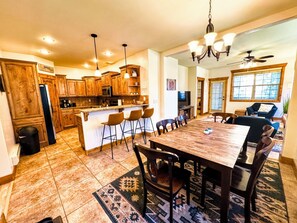 A spacious kitchen with wooden cabinets, a central island with bar stools, and a dining area with a large table and chairs.
