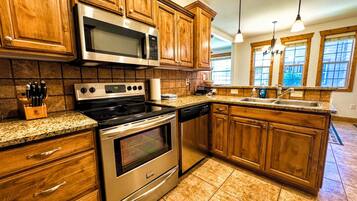 A kitchen with wooden cabinets, stainless steel appliances, granite countertops, and a window with a view.