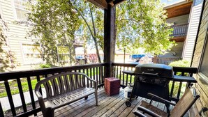 A wooden deck with a grill, a bench, and a gas canister. - Mountain Chic Condo Near Grand Targhee and Driggs (Driggs)