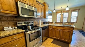 A kitchen with wooden cabinets, a stainless steel microwave, a gas stove, and a dishwasher.