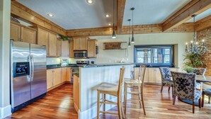 A modern kitchen with wooden cabinets, stainless steel appliances, and a central island with bar stools.