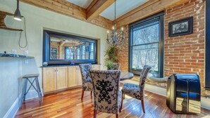 A kitchen with wooden beams, a large window, and a dining area with patterned chairs.